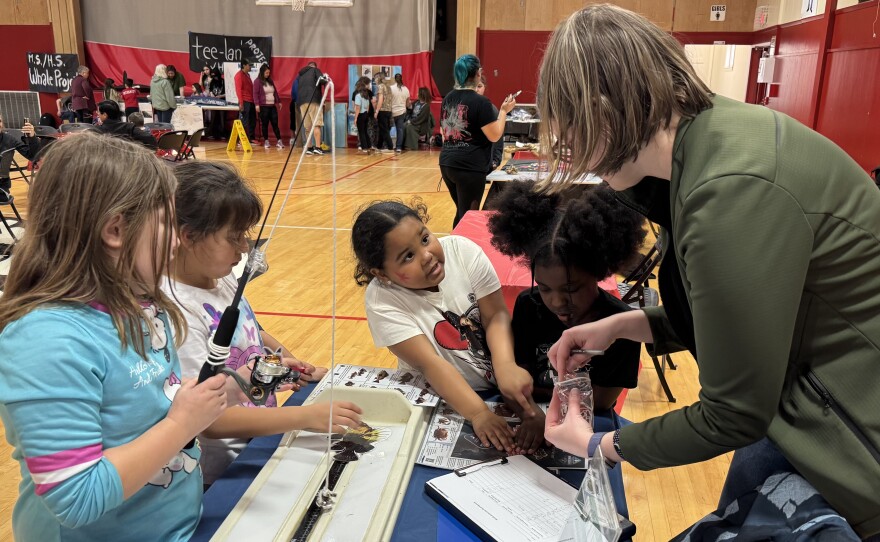 Three kids participating in a hook-and-line fishing demonstration activity with an ODFW employee.